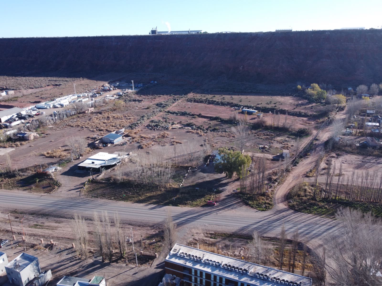 Vista aérea oblicua del lote con el desarrollo habitacional en primer plano y la barda de fondo
